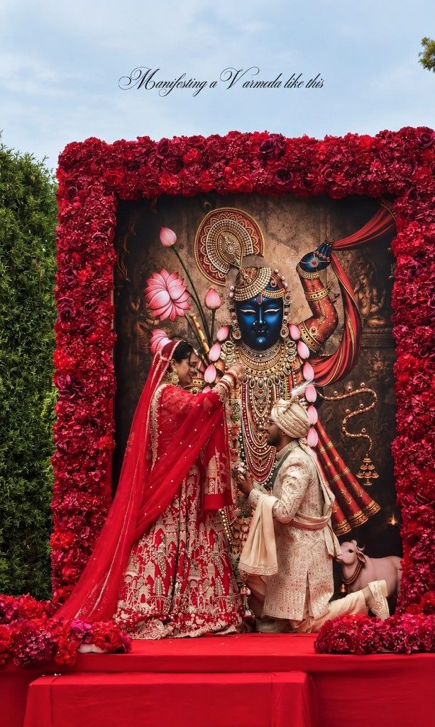 Couple on a red stage framed by roses for the varmala